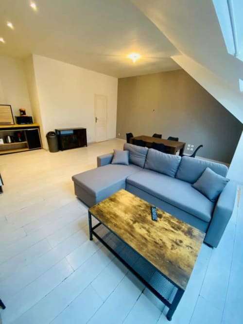 Studio moderne et cosy avec canapé sectionnel bleu, table en bois et revêtement blanc aux Business Apparts Caudry