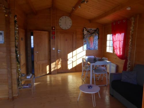 Intérieur spacieux d'un chalet en bois avec table à manger, coin salon et vue sur le lac de montagne aux Chalets de Lozzi