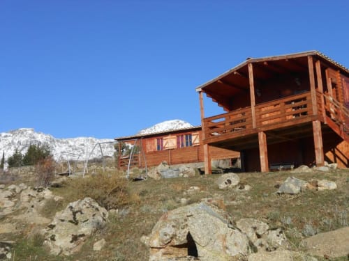 Chalet rustique en bois aux Chalets de Lozzi à Calacuccia, avec montagnes enneigées, jardin et terrasse extérieure