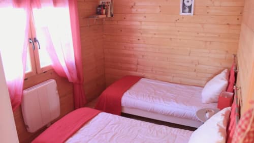 Chambre chaleureuse aux Chalets de Lozzi avec lits jumeaux, linge rose, boiseries et rideaux roses
