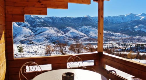 Montagnes enneigées et lac vus depuis le balcon d'un chalet en bois à Calacuccia avec salon de détente