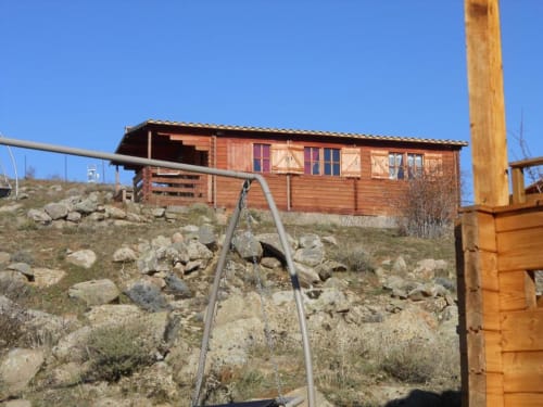 Chalet rustique en bois sur versant rocheux à Calacuccia avec vue sur le lac, terrasse en bois et cadre montagnard.