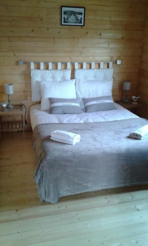 Chambre cosy dans un chalet en bois aux Chalets de Lozzi avec lit confortable et vue sur les montagnes