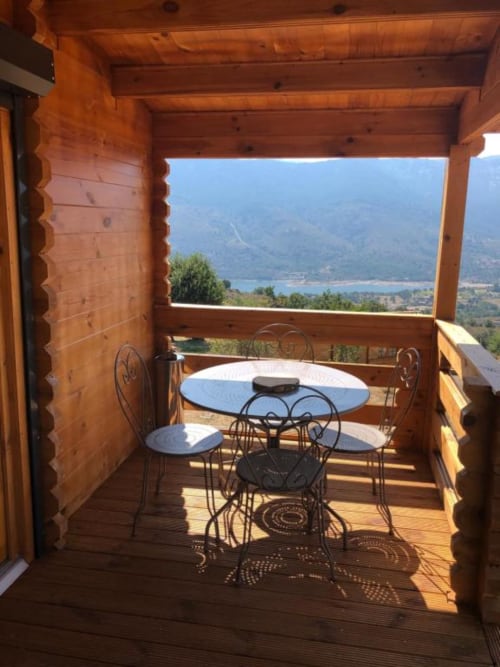 Terrasse en bois du chalet avec mobilier de salle à manger surplombant le lac de Calacuccia et les montagnes, Les Chalets de Lozzi