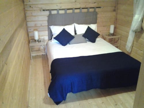 Chambre cosy du chalet Les Chalets de Lozzi avec lit queen, linge de lit bleu marine, murs en bois et parquet à Calacuccia.