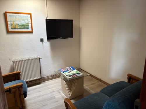 Séjour douillet de la Maisonnette avec TV écran plat, coin salon, radiateur et paysage montagneux encadré