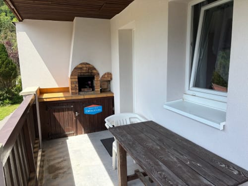 Terrasse ensoleillée avec table à manger, four à pizza en brique et vue sur les montagnes aux Gîtes les Grandes voies au Ménil