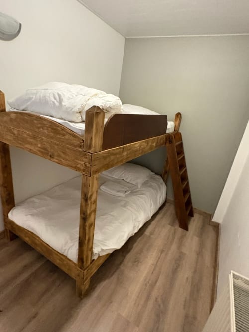 Wooden bunk bed with white bedding in cottage bedroom at Gîtes les Grandes voies, Le Ménil