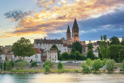 Picturesque riverside view of Gorrevod, France with twin church towers and historic buildings at sunset