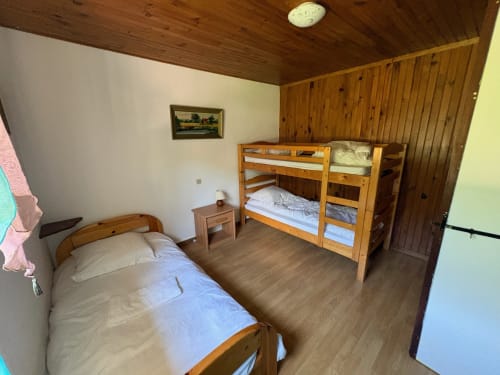 Bedroom in Gîte Jardin cottage with single bed, wooden bunk bed, and wood-paneled walls at Les Grandes voies