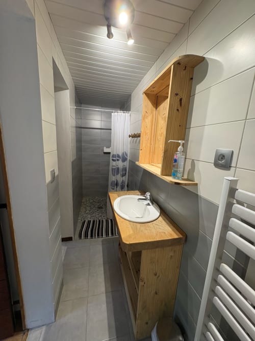 Modern bathroom with wooden vanity, round sink, mirror with shelves, and walk-in shower at Gîtes les Grandes voies cottage