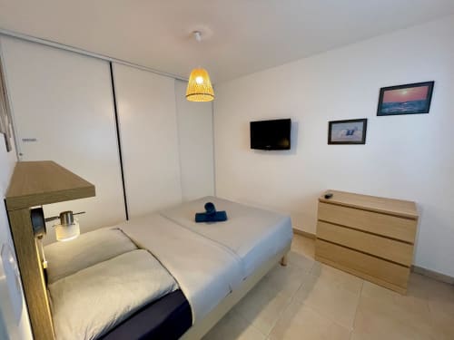 Modern beachside apartment bedroom at Marina di Bravone with twin beds, TV, wooden furniture and pendant lighting