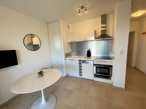 Modern open-plan kitchenette and dining area in T2 apartment at Résidence Marina di Bravone, Apennins, with white cabinetry