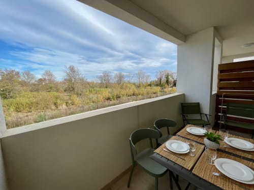 Modern balcony at Résidence Marina di Bravone with dining table, forest views, and contemporary design