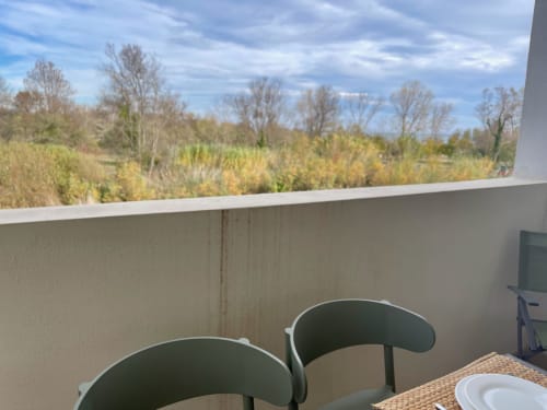 Balcony view at Marina di Bravone with green chairs overlooking autumn trees and landscaped grounds