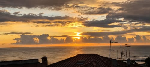 Tramonto drammatico sul Mar Tirreno dall'appartamento ViOletta a Lido di Ostia con nuvole dorate e sagome di tetti