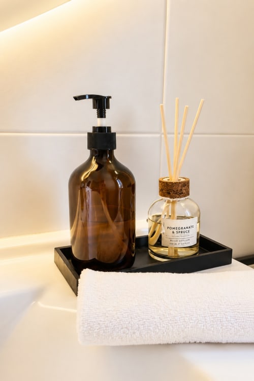 Esposizione di amenities del bagno ViOletta Oceanine 7: flacone in vetro ambrato, diffusore ambiente melograno e abete, bianco