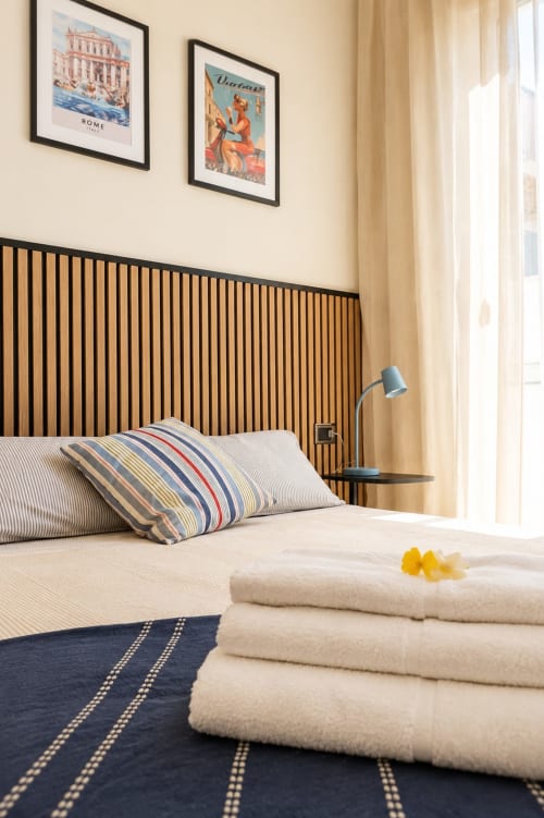 Camera moderna dell'hotel ViOletta a Lido di Ostia con letto a righe, testata in legno, poster vintage e vista sul mare