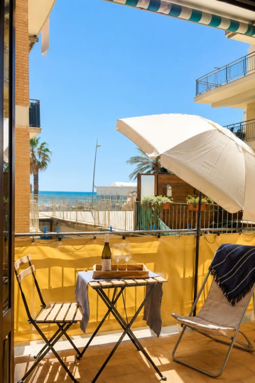 Balcone fronte mare dell'hotel ViOletta a Lido di Ostia con vista sul mare, ombrellone bianco e zona pranzo