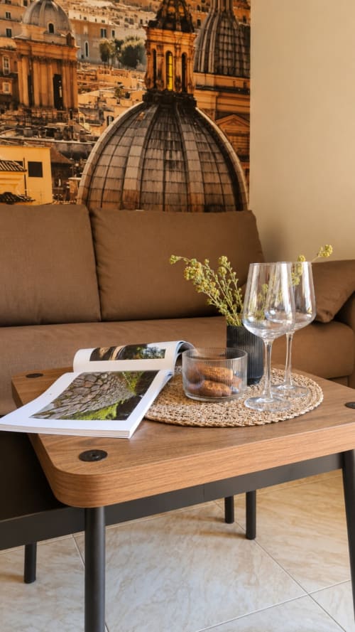 Elegante zona living a ViOletta, Lido di Ostia con tavolo in legno, bicchieri di vino e poster con sfondo architettonico italiano