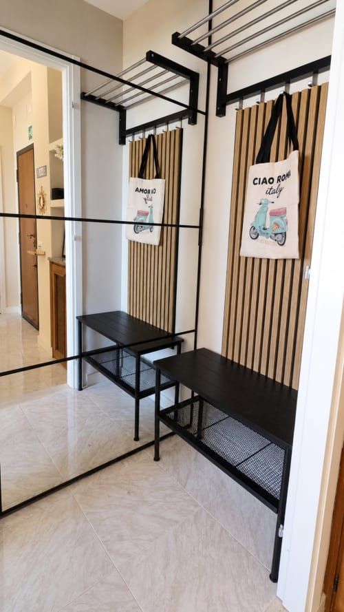 Entrata moderna dell'hotel ViOletta a Lido di Ostia con panche nere in metallo, pannelli in doghe di legno e tema italiano