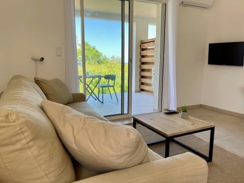 Moderno monolocale a Marina di Bravone con divano beige, balcone vista mare, TV e accesso spiaggia a Linguizzetta.