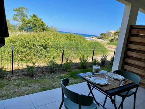 Terrazza di monolocale fronte mare alla Résidence Marina di Bravone con zona pranzo, vista sul mare e giardino mediterraneo