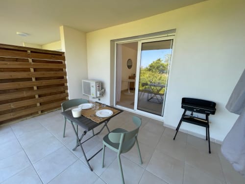 Terrazza dello studio a Marina di Bravone con area pranzo, vista mare attraverso le porte in vetro e barbecue elettrico acceso
