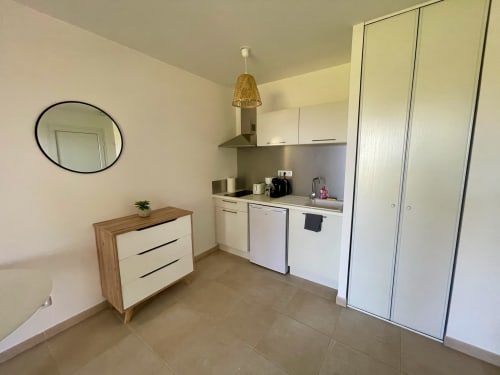 Cucina moderna e zona living alla Résidence Marina di Bravone, Linguizzetta, con elettrodomestici bianchi e credenza in legno