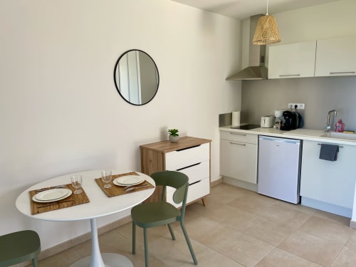 Cucina e zona pranzo moderne del monolocale a Résidence Marina di Bravone con tavolo ovale bianco e sedie verdi