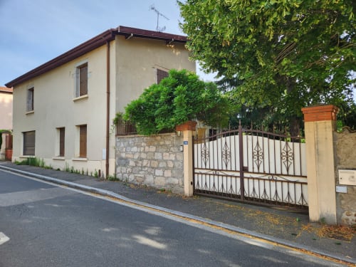 Charmante villa à Charly avec murs de pierre, entrée couverte de lierre, portail blanc et vue sur le jardin