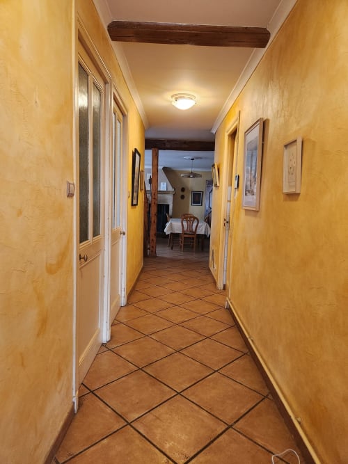 Couloir jaune vif aux carrelages en terre cuite menant à la cuisine et à l'espace repas de la villa Charly