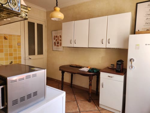Spacieuse cuisine de villa à Charly : meubles blancs, table en bois, électroménagers modernes, vue sur jardin
