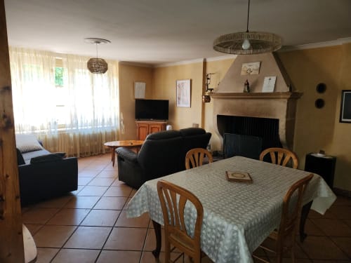 Spacieux salon de villa avec table à manger, canapé noir, foyer, téléviseur et vue sur le jardin à Charly, France
