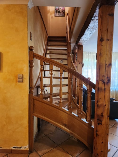 Escalier en bois à balustres dans le couloir de la villa aux murs jaunes, menant à l'étage supérieur de la propriété Charly