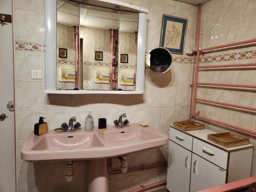 Salle de bains rose avec double vasque, miroir et sèche-serviettes chauffant dans une villa française