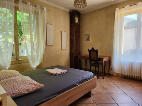 Spacieuse chambre avec lit double, bureau en bois, chaise et vue sur le jardin à Jolie Maison à Charly