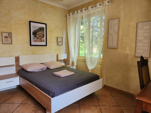 Chambre spacieuse de villa à Charly avec lit moderne, murs jaunes, vue sur jardin par portes-fenêtres et style contemporain