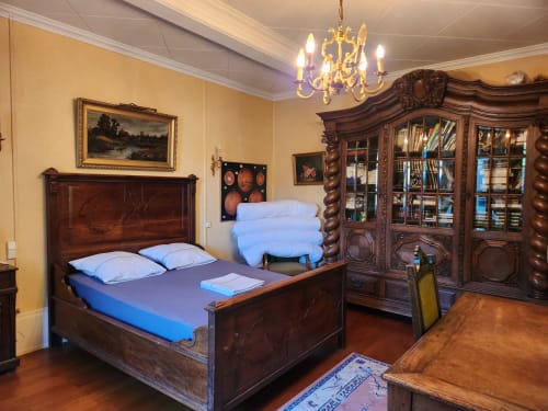 Chambre élégante dans une villa française avec mobilier en bois foncé, literie bleue, lustre et décor ancien à Charly