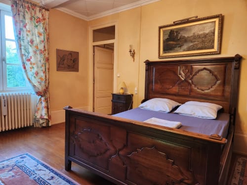 Chambre élégante avec lit en bois, murs jaunes, rideaux fleuris et mobilier classique dans une villa française