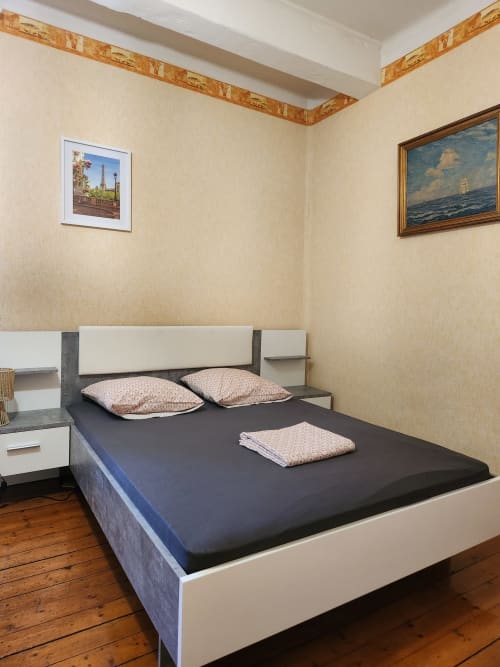 Chambre moderne avec lit foncé, tête de lit beige et deux coussins à motifs à la villa Charly avec vue sur le jardin et œuvres encadrées