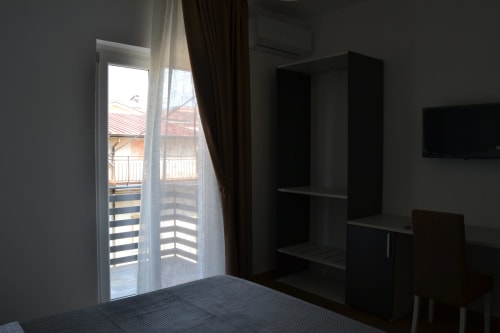 Modern bedroom at Makasa B&B in Villapiana with balcony door, black shelving unit, and city views