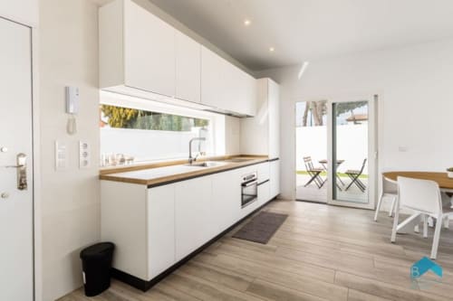 Cocina moderna con muebles blancos, encimeras de madera y acceso a patio en Barrosa Home, España