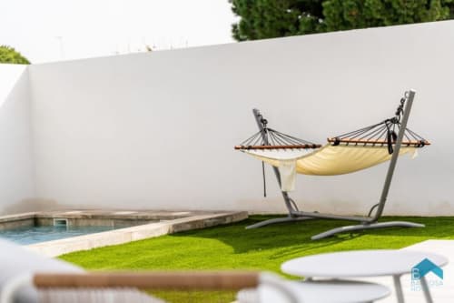 Hamaca amarilla en la terraza de césped con piscina de Barrosa Home, España