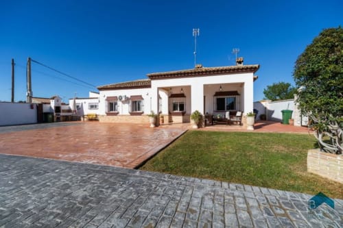 Villa blanca Barrosa en España con patio de terracota, jardín verde y arquitectura mediterránea
