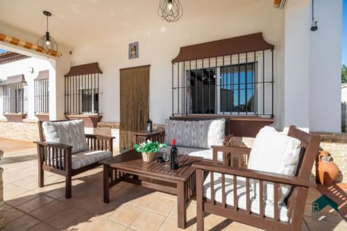 Terraza de Barrosa Home con muebles de madera, asientos acolchados y ventanas con rejas con vistas al campo español