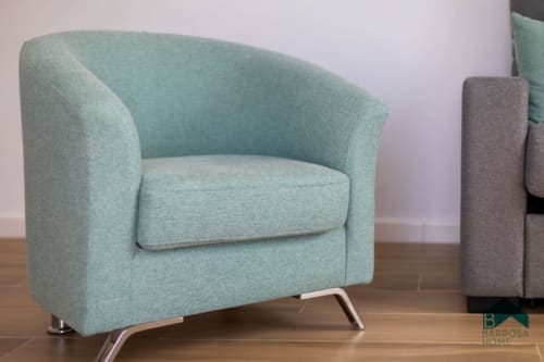 Modern mint-green armchair with metal legs at Barrosa Home hotel, featuring contemporary design on wooden flooring