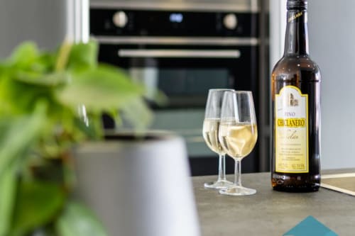 Botella de jerez Fino Chiclanero con copas servidas en la cocina de Barrosa Home, España