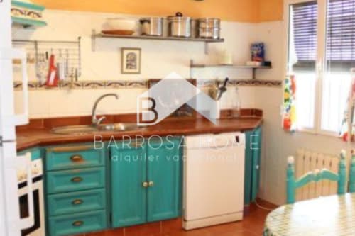 Cocina luminosa en Barrosa Home con gabinetes turquesas, encimera de madera y electrodomésticos crema