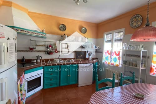 Cocina colorida en Barrosa Home con muebles turquesas, paredes naranjas y mesa de comedor